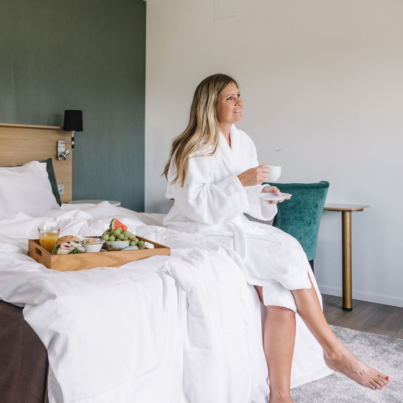 Woman in bathrobe enjoying breakfast in bed