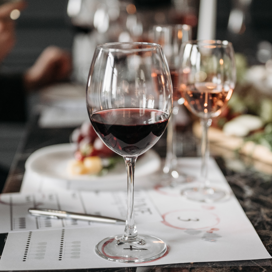 Vinsglas med rött vin på restaurangbord med suddig restaurangmiljö i bakgrunden