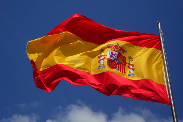 Spaniens flagga vajar mot blå himmel